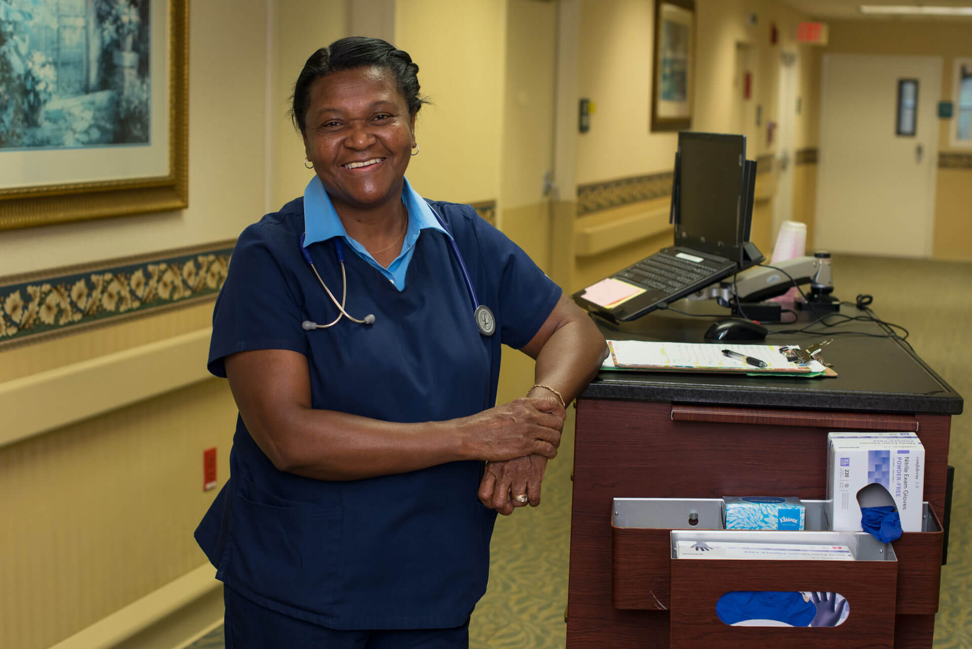 Nurse smiling and standing next to work station.